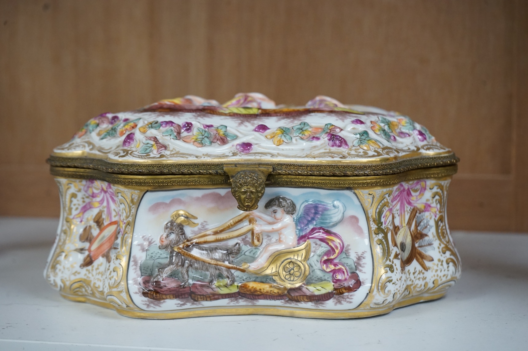 An ornate Neapolitan Capodimonte porcelain box with gilt mounts, 22cm wide, 11cm high